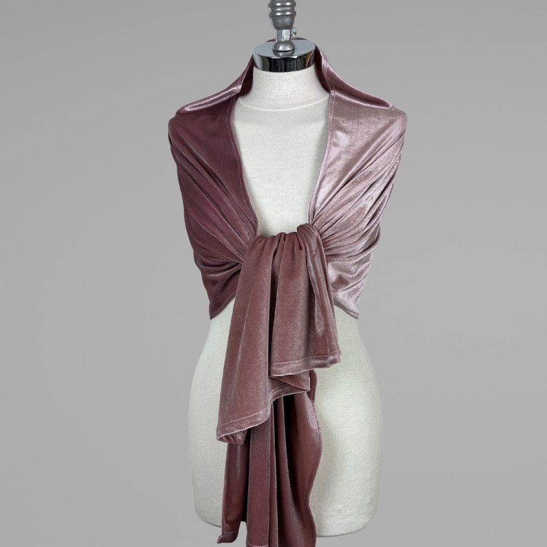May include: A dusty rose velvet shawl draped over a mannequin. The shawl is tied in a knot at the front and the ends are left to hang down.