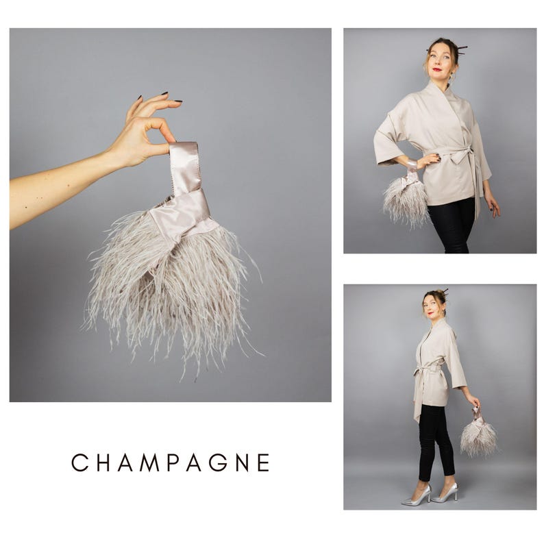 May include: A champagne-coloured clutch bag with a satin handle and a fluffy feather trim. The word "CHAMPAGNE" is printed in a minimalist font at the bottom of the image. The clutch is held up by a hand.