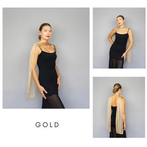 May include: A gold-colored scarf draped over a black dress. The scarf is rectangular and appears to be made of a sheer fabric. The word "GOLD" is printed in a minimalist font at the bottom of the image.