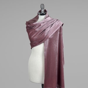 May include: A dusty rose velvet shawl draped over a mannequin. The shawl is soft and luxurious, perfect for adding a touch of elegance to any outfit.
