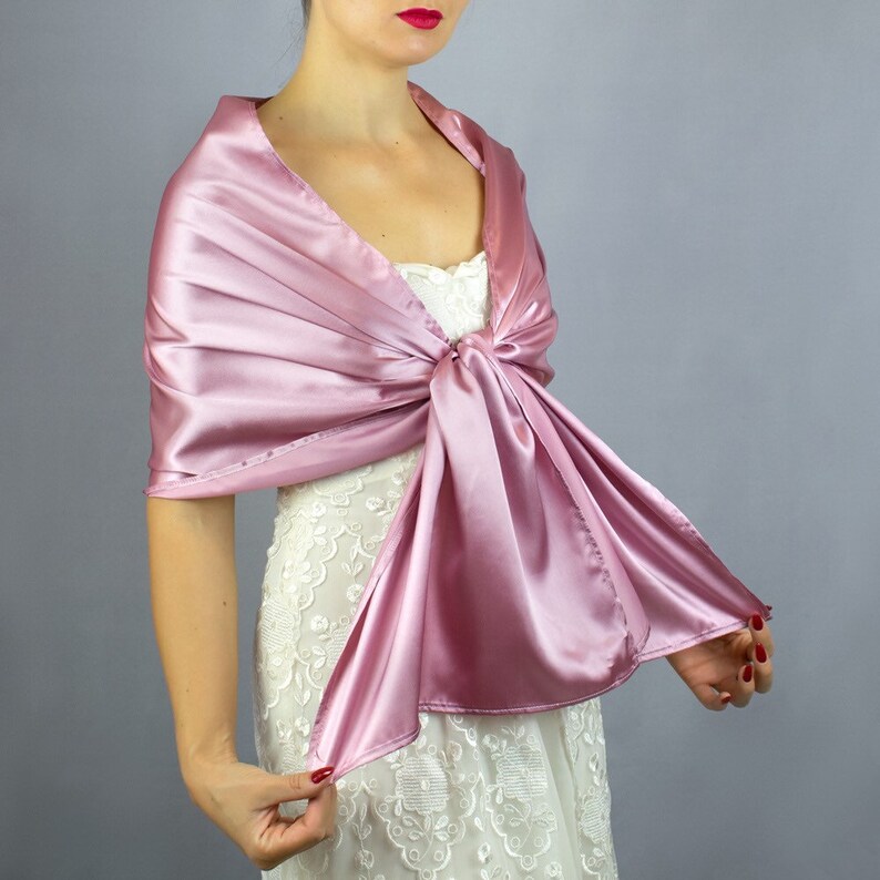 May include: A dusty rose satin shawl with a long, flowing design. The shawl is tied in a knot at the front and drapes down the front of the wearer.