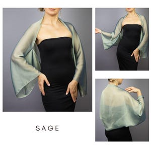 Pode incluir: Envolt&oacute;rio transparente verde s&aacute;lvia, estilo quimono, com mangas largas. &Eacute; usado sobre um vestido preto. A palavra "SAGE" est&aacute; impressa em branco na parte inferior da imagem. O tecido parece leve e fluido.