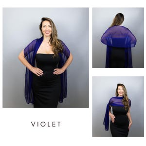 May include: A woman wearing a violet sheer shawl over a black dress. The shawl is draped over the shoulders and arms. The word "VIOLET" is printed in white at the bottom of the image. The background is a solid grey.