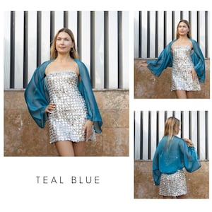 Pu&ograve; includere: Un bolero trasparente blu teal sopra un miniabito argentato con paillettes. Il bolero ha maniche lunghe e fluide. L'abito &egrave; senza maniche con scollatura dritta. L'immagine include il testo "TEAL BLUE".