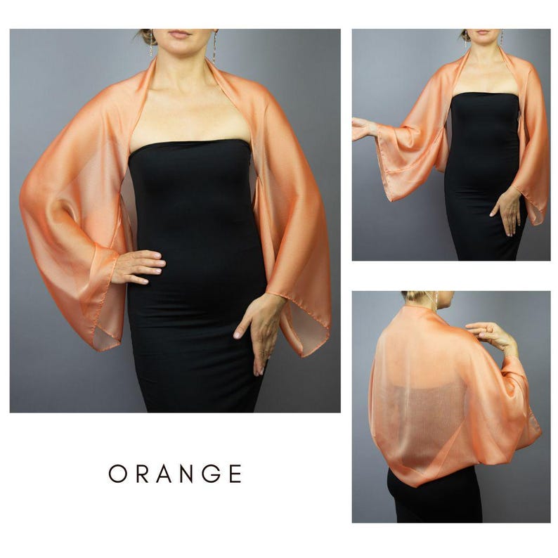 Pu&ograve; includere: Uno scialle di seta arancione con maniche ampie. Lo scialle &egrave; drappeggiato su un vestito nero. La parola "ORANGE" &egrave; stampata in bianco in basso nell'immagine. Lo scialle &egrave; un tessuto leggero e fluido.