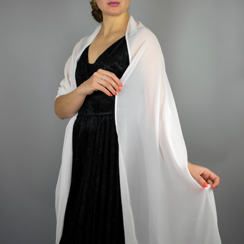 May include: A white chiffon shawl draped over a black dress. The shawl is sheer and lightweight, and it would be perfect for a special occasion.