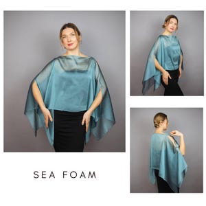 K&ouml;nnte beinhalten: Ein seegr&uuml;nes Cape-Top mit offenen &Auml;rmeln. Das Oberteil ist aus einem transparenten, flie&szlig;enden Stoff gefertigt und wird mit einem schwarzen Rock kombiniert. Der Text "SEA FOAM" wird in einer klaren, serifenlosen Schrift angezeigt.