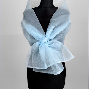 May include: A light blue sheer shawl tied in a bow at the neck. The shawl is made of a delicate, lightweight fabric.