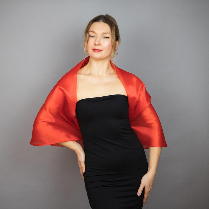 May include: A woman wearing a black strapless dress with a bright orange shawl draped over her shoulders.