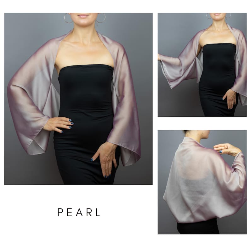 Pode incluir: Um xale perolado, semelhante &agrave; seda, com mangas largas. O xale apresenta um gradiente de lavanda e prata, drapeado sobre um vestido preto. A palavra "PEARL" &eacute; impressa em uma fonte minimalista na parte inferior da imagem.