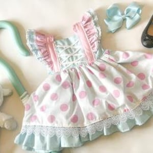 May include: A blue and pink polka dot dress with white lace trim and pink ruffles. The dress has a white criss-cross bodice and comes with a matching blue bow and a shepherd's crook.