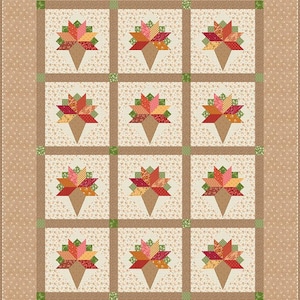 Könnte beinhalten: Ein rechteckiger Quilt mit einem Raster aus zwölf Blöcken, die jeweils ein zusammengesetztes Eiswaffel-Motiv aus roten, orangen, gelben und grünen Stoffen zeigen. Die Blöcke liegen auf einem cremefarbenen Blumenhintergrund mit braunen Zwischenstreifen.