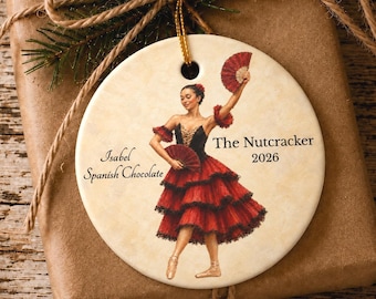 Könnte beinhalten: Ein rundes Keramikornament mit einer Tänzerin in einem schwarz-roten Stufenkleid, die einen roten Fächer hält. Der Text lautet Isabel Spanish Chocolate, The Nutcracker und 2026. Das Ornament hat eine goldene Aufhängung und einen cremefarbenen Hintergrund.