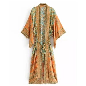 May include: A long-sleeved kimono robe featuring a vibrant orange base color with intricate teal and gold floral patterns throughout. The garment includes a matching fabric tie belt at the waist and a vertical border design along the front opening.