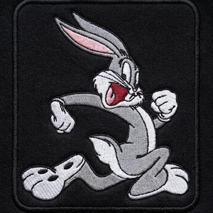 May include: Embroidered patch featuring Bugs Bunny in a running pose. The cartoon rabbit is depicted in gray, white, and pink, with a wide-open mouth. The patch is rectangular with rounded corners and a black background.