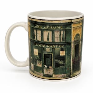 May include: A white ceramic mug featuring a printed illustration of a green storefront with the text Chez JEROME and RESTAURANT 62. The design depicts a multi-story building facade with large windows, a central door, and architectural details.