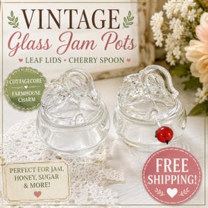May include: Two clear glass jam pots with leaf-shaped lids and a cherry spoon. The image includes text that reads "VINTAGE Glass Jam Pots" and "COTTAGECORE FARMHOUSE CHARM". The pots are on a white lace doily.
