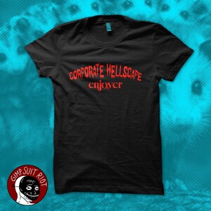 May include: Black t-shirt with the red text "CORPORATE HELLSCAPE enjoyer". The shirt has a crew neck and short sleeves. A logo with a smiling face is in the lower left corner.