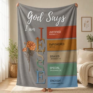 May include: A gray fleece blanket featuring the text God Says I am JESSE vertically in multi-colored letters next to a marigold illustration. Five colored rectangles list the words JUSTIFIED, EMPOWERED, SEALED, SPECIAL, and ENOUGH with Bible verses.