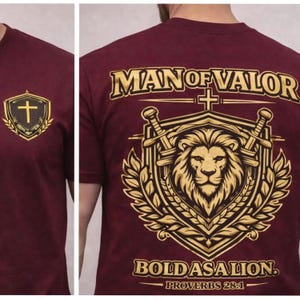 Puede incluir: Camiseta granate con gráficos dorados. La parte delantera presenta una cruz dentro de un escudo y una corona de laurel. La parte trasera muestra "MAN OF VALOR" sobre una cabeza de león, espadas y el texto "BOLD AS A LION. PROVERBIOS 28:1."