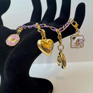 Pulsera de cadena de esmalte dorado y morado con dijes marcadores de puntadas dorados. imagen 3