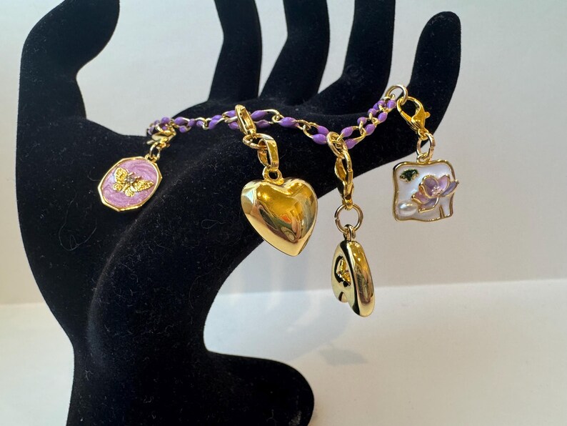 Pulsera de cadena de esmalte dorado y morado con dijes marcadores de puntadas dorados. imagen 3