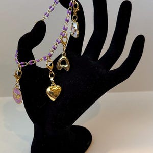 Pulsera de cadena de esmalte dorado y morado con dijes marcadores de puntadas dorados. imagen 1