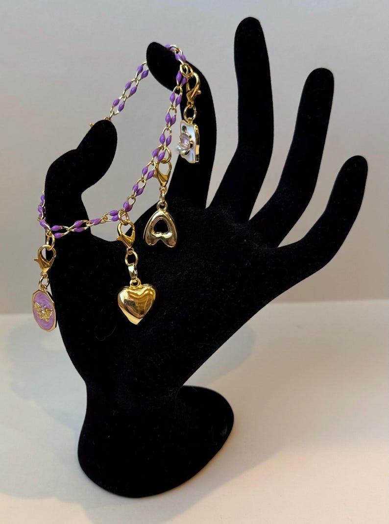 Pulsera de cadena de esmalte dorado y morado con dijes marcadores de puntadas dorados. imagen 1