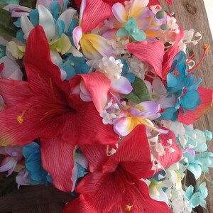 May include: A bouquet of artificial flowers with red, white, blue, and yellow flowers. The bouquet features a large red lily and smaller flowers in various shades of blue and white.