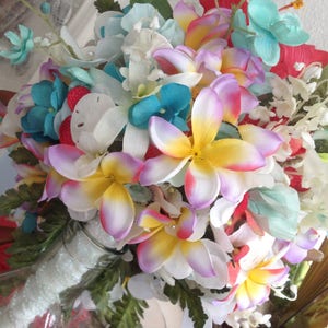 May include: A bouquet of artificial flowers in shades of white, pink, yellow, blue, and red. The flowers are arranged in a clear glass vase with a white, sparkly ribbon.