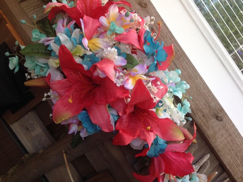 May include: A bouquet of artificial flowers with red lilies, blue hydrangeas, and white and yellow flowers.