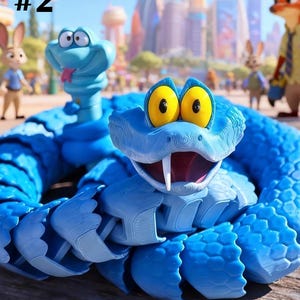 May include: A blue articulated snake toy with a textured scale pattern, large yellow eyes, and a white fang. The figure is coiled on a wooden surface with a blurred background featuring cartoon characters and a city skyline. The text #2 is visible.
