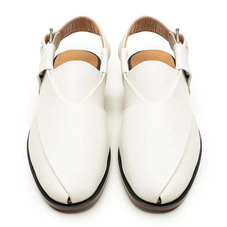 Puede incluir: Un par de sandalias de cuero blanco con un dise&ntilde;o &uacute;nico. Las sandalias tienen una correa en el tobillo con cierre de hebilla. Las suelas son negras con un borde marr&oacute;n. Las sandalias miden aproximadamente 25 cm de largo.