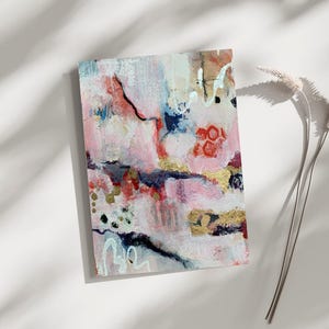 May include: Abstract art piece with a blend of pink, red, blue, and gold paint. The artwork features textured brushstrokes and a mix of colors, creating a modern and artistic aesthetic. The piece is rectangular and appears to be on canvas.