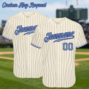 Puede incluir: Dos camisetas de béisbol color crema con rayas verticales azul marino. Cada camiseta tiene la palabra "Teamname" en escritura azul claro, y el número "00" en una de ellas. El texto "Custom Any Request" está en la parte superior.