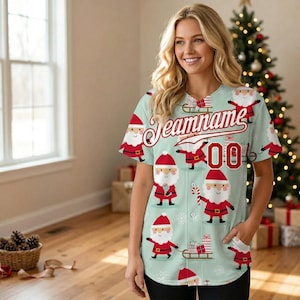 Puede incluir: Una camiseta de béisbol verde claro con un estampado de Papá Noel. La camiseta tiene la palabra "Teamname" en escritura roja en el pecho, con el número "00" en rojo. Ilustraciones de Papá Noel están dispersas por la camiseta.
