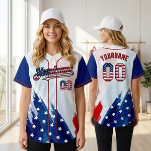Puede incluir: Camiseta de béisbol blanca, azul y roja. La parte delantera tiene "Yourteams" y el número "00". La parte trasera muestra "YOURNAME" y el número "00", ambos con un diseño inspirado en la bandera estadounidense. Un diseño deportivo y patriótico.