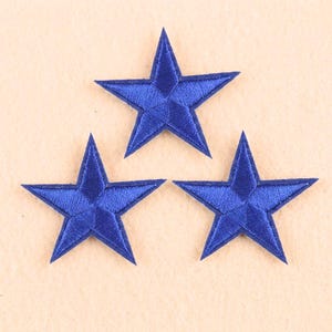 May include: Three blue star-shaped embroidered patches. Each star has five points and is a vibrant shade of blue with darker blue stitching. The patches are likely for decorative purposes, such as embellishing clothing or accessories.