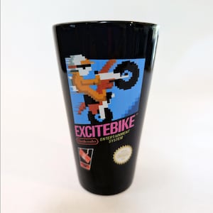 May include: Black glass featuring the Excitebike logo and pixelated graphic of a motocross rider on a blue background. The glass also includes the Nintendo logo and the words "Entertainment System."