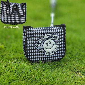 May include: Black and white houndstooth golf club cover with a black trim. The cover has a white patch with the text "PGM4G", a smiling face, and the words "Ready Golf". A second cover is visible in the background.