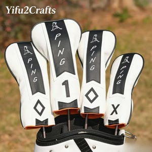 May include: Set of four white and black golf club head covers with the brand name "PING" and a number or letter on each. The covers have an orange trim and are in a golf bag. The brand name "Yifu2Crafts" is in the top left corner.