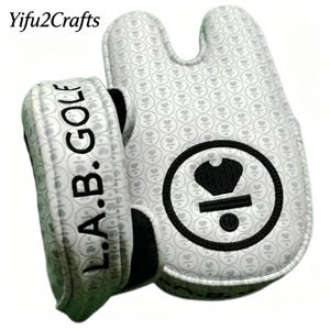 May include: White golf putter cover with a heart pattern and the text "L.A.B. GOLF". The cover has a black and white circular logo with a crown design. The cover is designed to protect golf clubs.