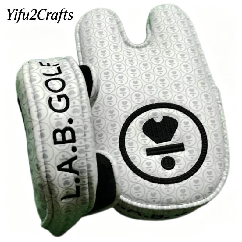 May include: White golf putter cover with a heart pattern and the text "L.A.B. GOLF". The cover has a black and white circular logo with a crown design. The cover is designed to protect golf clubs.