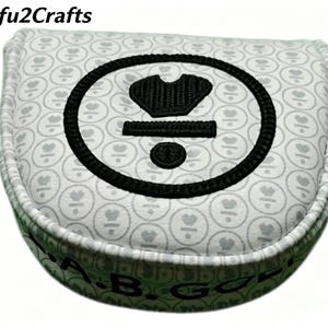 May include: A golf club head cover with a white background and a repeating pattern of gray hearts. The cover features a large black embroidered design and the text "A.B. GOLF" in green.