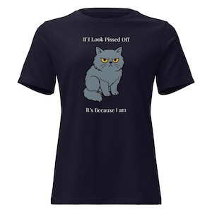 Puede incluir: Camiseta azul marino con un gato de dibujos animados gruñón con ojos amarillos. El texto encima del gato dice "If I Look Pissed Off" y debajo, "It's Because I am". El gato es gris con la barriga blanca.