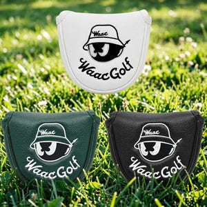 Könnte beinhalten: Drei Golfschlägerhauben in Weiß, Grün und Schwarz. Jede Haube zeigt ein Cartoon-Auge mit Hut und dem Text "Waac Golf" in Schreibschrift. Die Hauben liegen auf einer grünen Grasfläche.