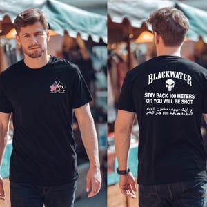 Peut inclure: Un t-shirt noir avec un petit motif sur la poitrine représentant deux drapeaux croisés et le mot ALUMNI. Le dos porte l'inscription BLACKWATER, une icône de crâne et l'avertissement STAY BACK 100 METERS OR YOU WILL BE SHOT en anglais et arabe.
