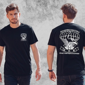 Könnte beinhalten: Ein schwarzes kurzärmeliges T-Shirt mit weißem Grafikdruck. Die Vorderseite zeigt ein kleines Fallschirm-Emblem mit griechischem Text. Die Rückseite zeigt eine große Grafik eines Fallschirms, eines Delfins und Tauchausrüstung mit dem Text O.Y.K.