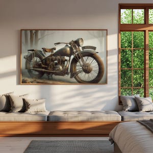 Op de afbeelding: Een ingelijste prent van een vintage motorfiets. De motorfiets heeft een donkere, gedempte kleur met een grote voorband en een koplamp. De achtergrond is een vage, sepia-getinte landschap met bomen.