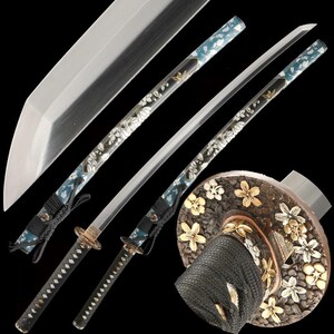 Op de afbeelding: Twee Japanse katana-zwaarden met zilveren bladen en sierlijke handvatten. De handvatten zijn omwikkeld met zwart koord en hebben een bloemmotief met gouden en witte accenten. De scheden zijn blauw met witte bloempatronen. De zwaardbescherming is rond met bloemsnijwerk.